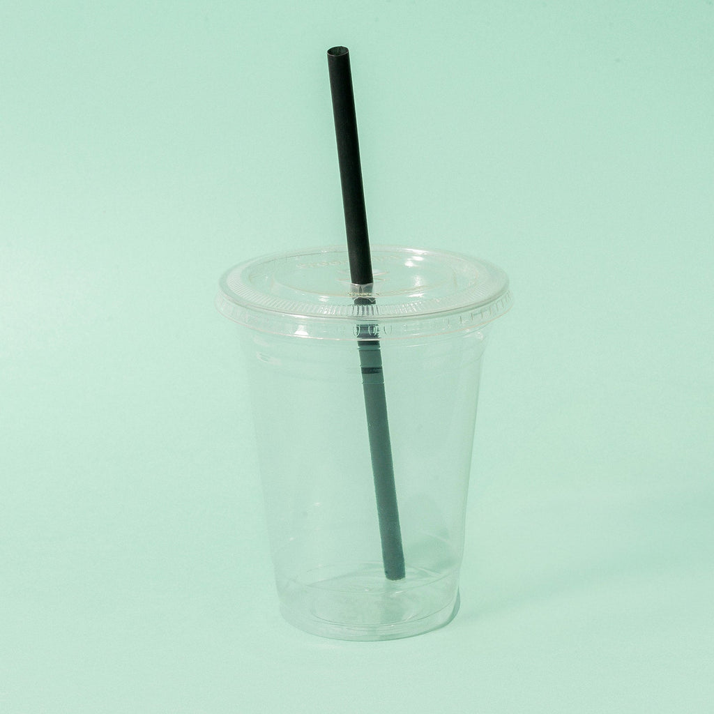 Clear cup with a black straw and compostable lid on a light green background
