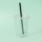 Clear cup with a black straw and compostable lid on a light green background