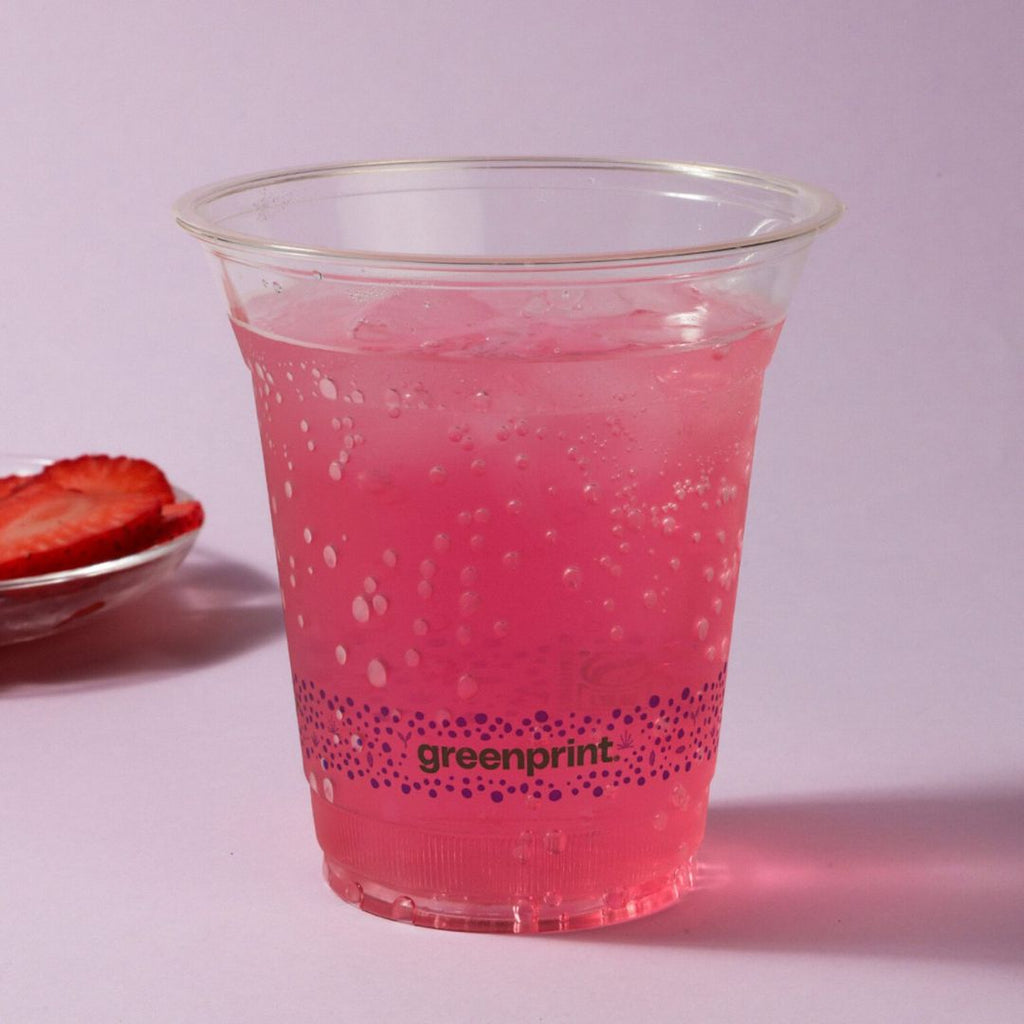 Clear cup with pink drink and 'greenprint' branding on a light purple background