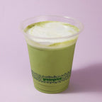 Green smoothie in a clear compostable plastic cup with 'greenprint' branding on a light purple background