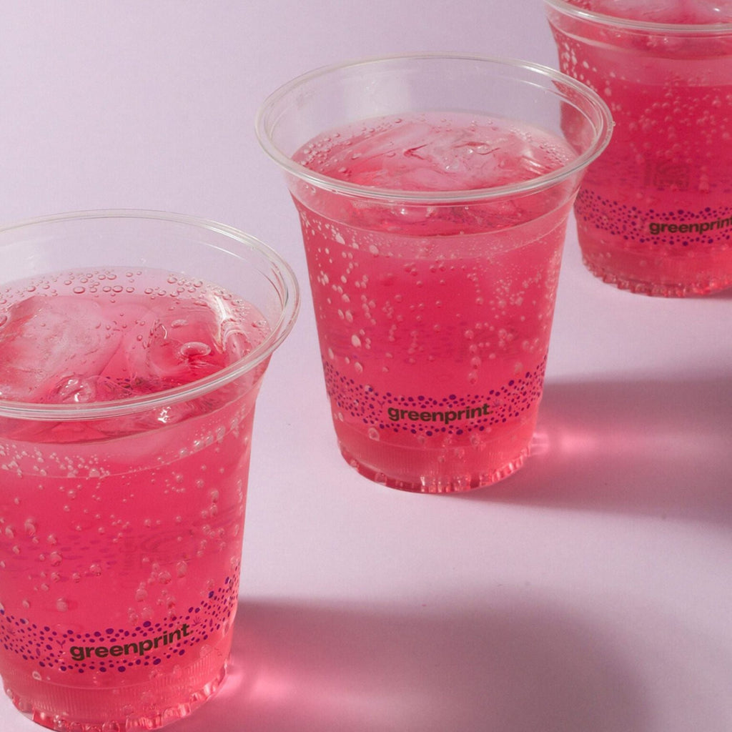 Three clear cups filled with pink bubbly drink on a white background