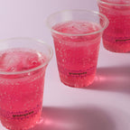 Three clear cups filled with pink bubbly drink on a white background