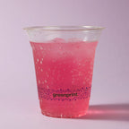 Clear plastic cup with pink drink and 'greenprint' branding on a light purple background