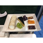 Assorted food items including crackers, cheese, grapes, nuts, and dried fruits on a balsa wood tray.