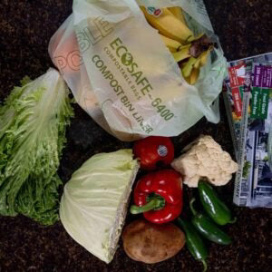 Compostable produce bag with groceries on a compost pile