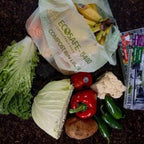 Compostable produce bag with groceries on a compost pile