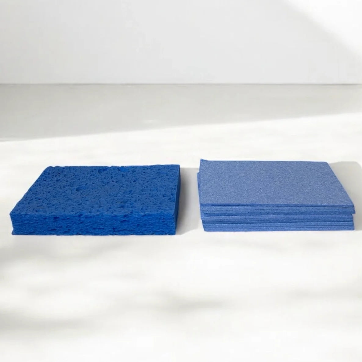 Two stacks of blue sponges on a white background