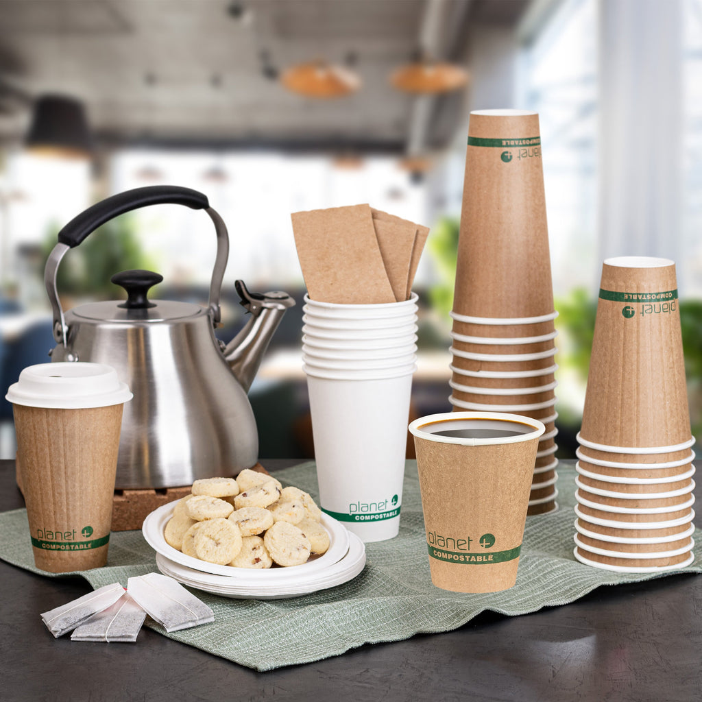 Stacks of paper cups and a kettle on a table with a blurred kitchen background