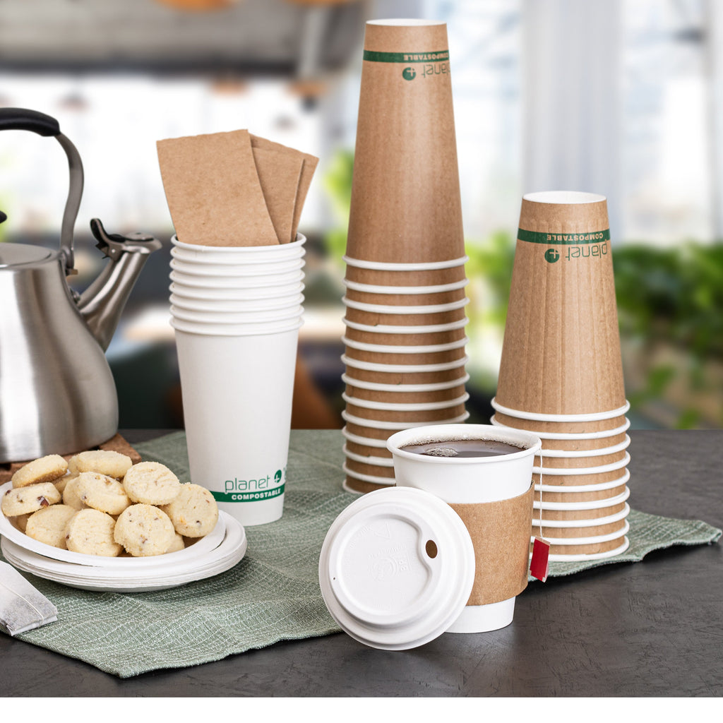 Stacks of paper cups and a kettle on a table with a blurred background