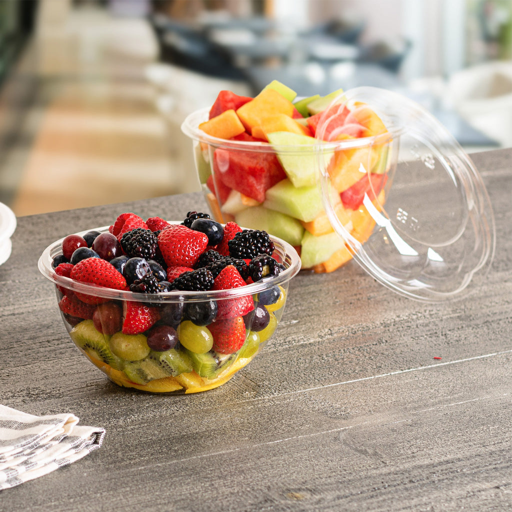 Two plastic containers with lids containing assorted fruits on a table
