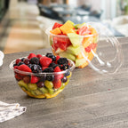Two plastic containers with lids containing assorted fruits on a table