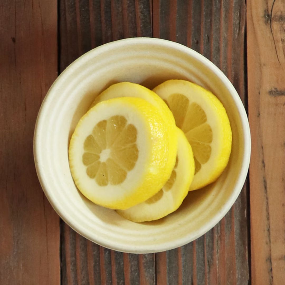 Sliced lemons in a compostable bowl on a wooden surface