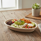 Colorful salad in a compostable fiber bowl on a wooden table with a plant in the background