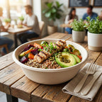 Vegetarian bowl with skewer, avocado, and vegetables in a compostable bowl on a wooden table in a restaurant setting.