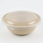 Compostable fiber bowl with a clear lid on a white background