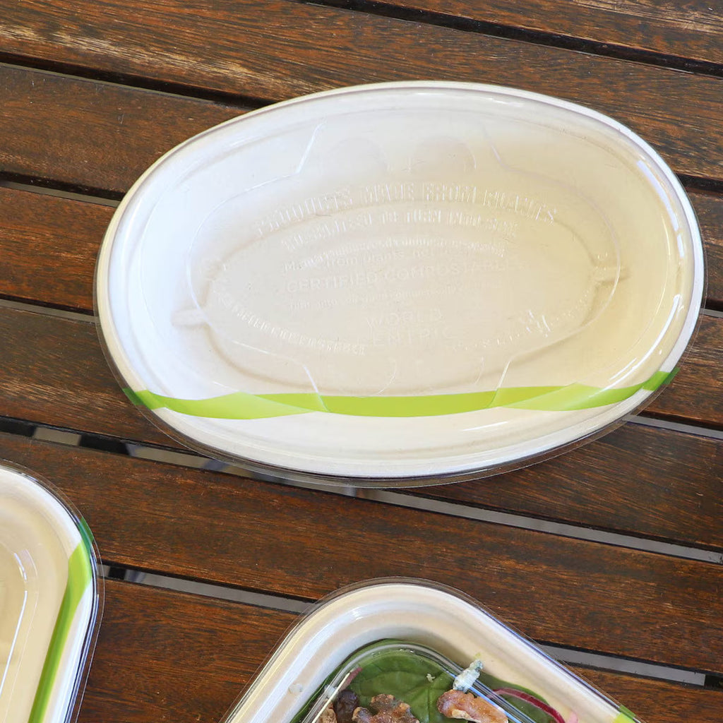 Compostable burrito bowl with lid that has a green stripe on a wooden surface
