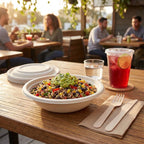 Compostable bowl of salad with guacamole on a wooden table outdoors