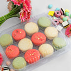 Clear compostable small treat container with colorful macarons with flowers and candy nearby.