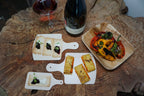 Several different sized cheeseboards with appetizers on a tree stump table.