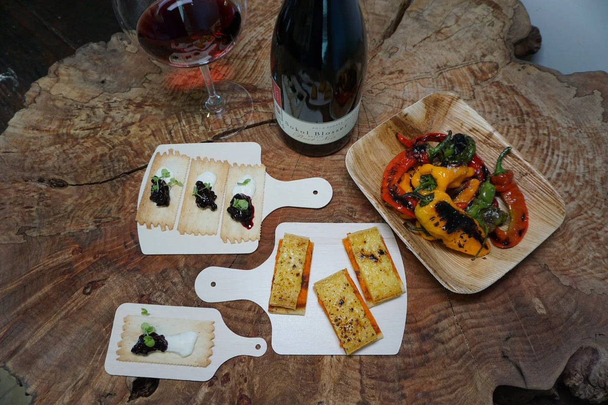 Several different sized cheeseboards with appetizers on a tree stump table.
