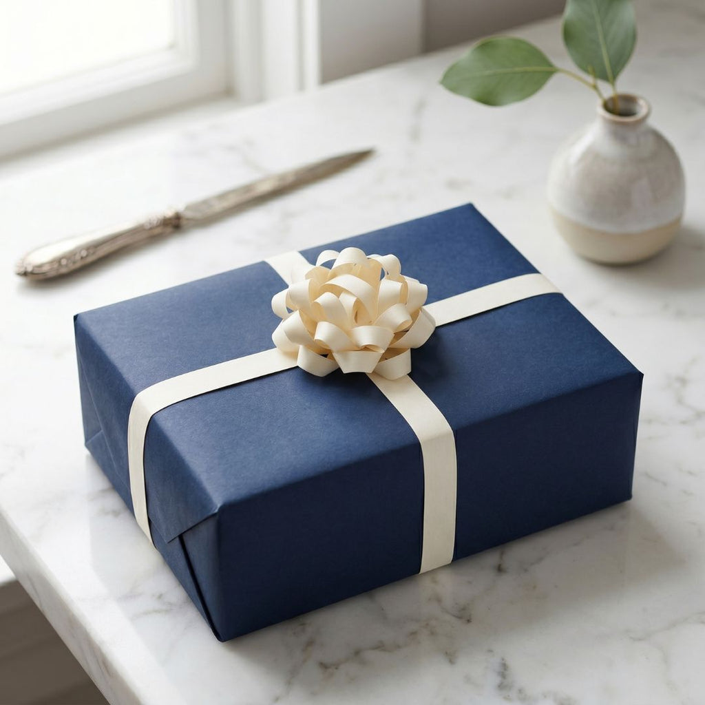 Blue gift box with a cream ribbon and bow on a marble surface.