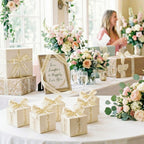 Decorative table setting with gift boxes wrapped with wedding ribbon, flowers, and a framed sign in a bright room.