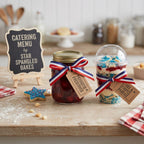 Jars of preserves and a dessert with patriotic ribbons on a wooden table.