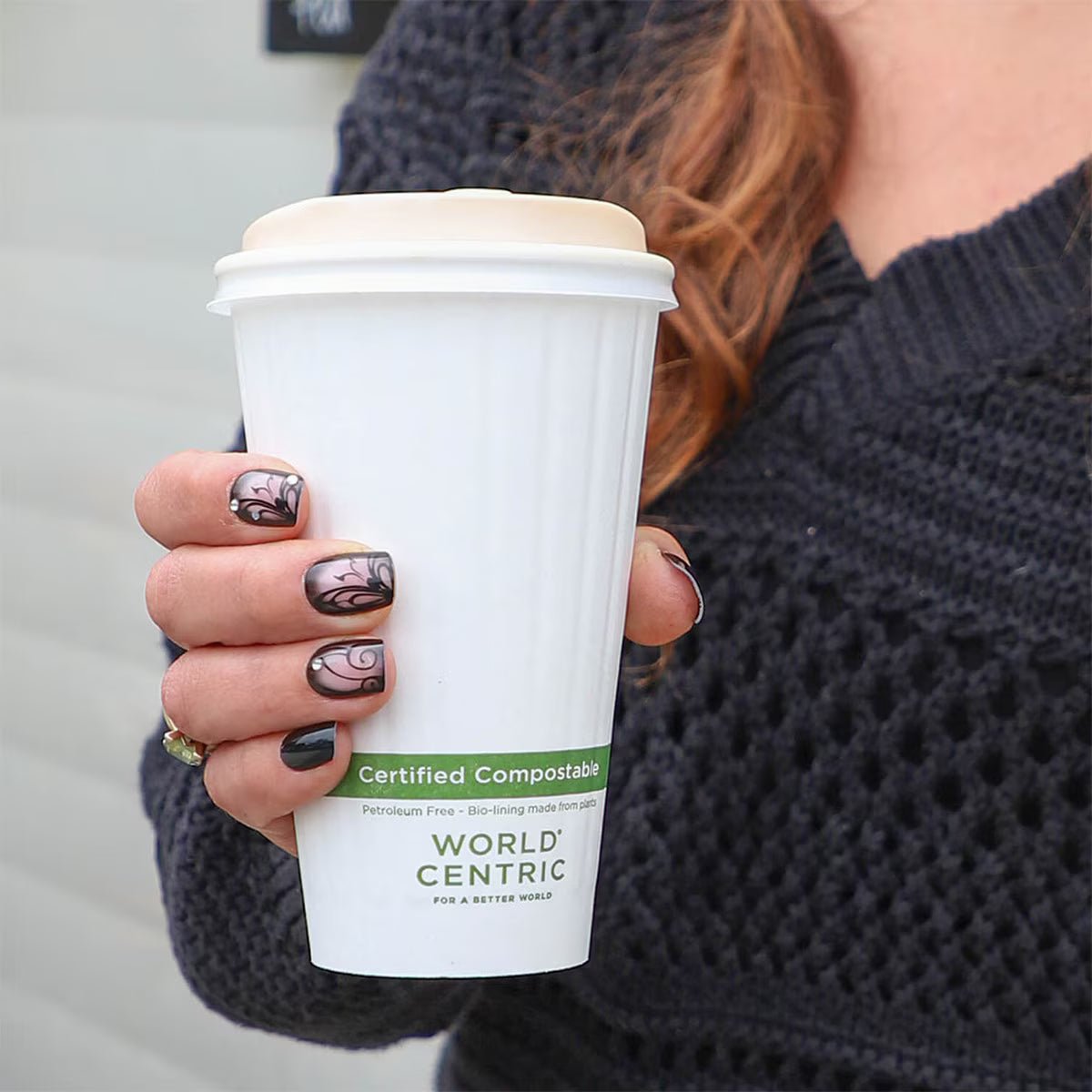 Person holding a World Centric compostable coffee cup