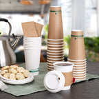 Stacks of paper cups with a kettle and cookies on a table