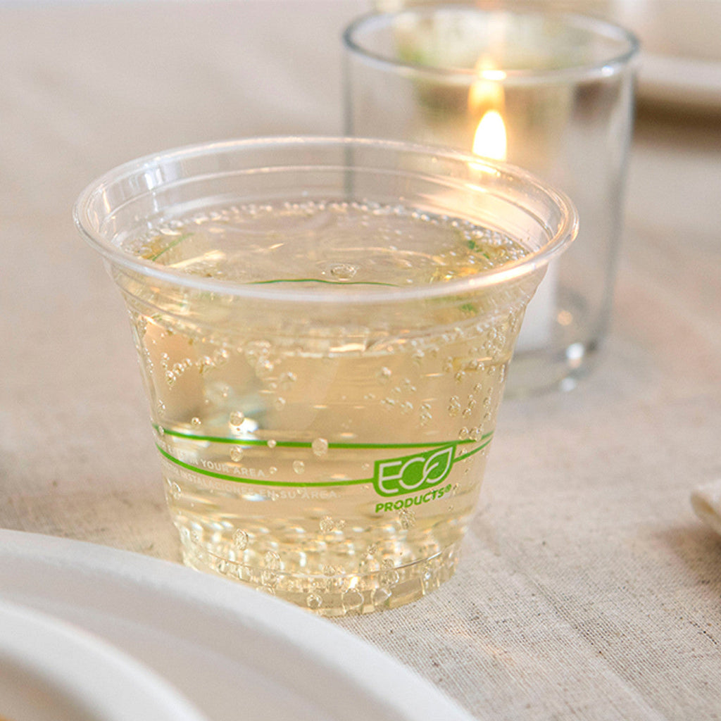 Clear plastic cup with green 'Eco' branding filled with a clear liquid on a textured surface.