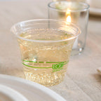 Clear plastic cup with green 'Eco' branding filled with a clear liquid on a textured surface.