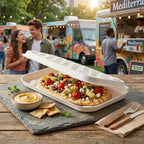 Pizza with various toppings inside a disposable flatbread box on a wooden table in front of food trucks, with a couple in the background.