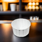 White compostable condiment cup on a dark surface with blurred shelves in the background