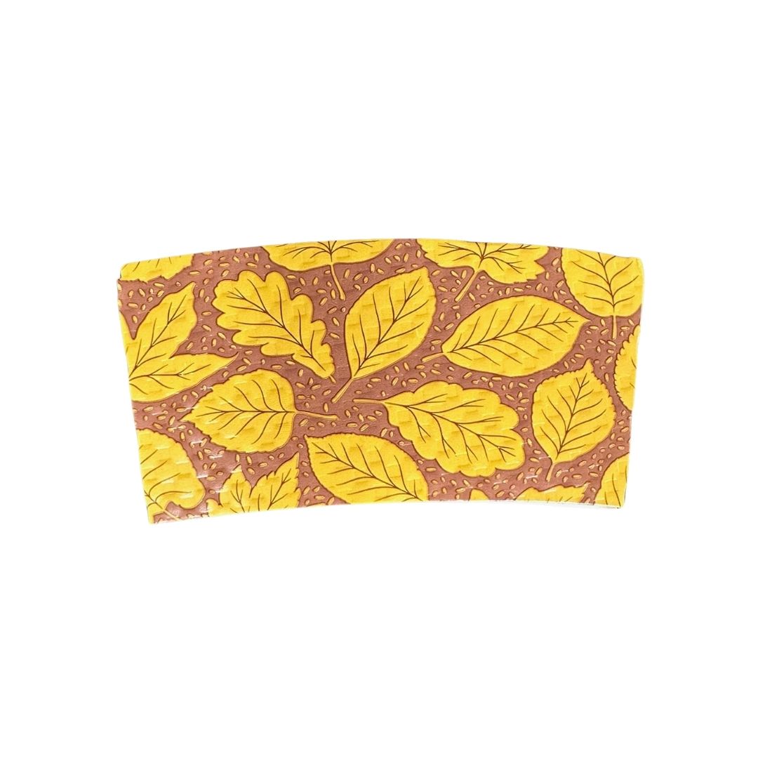 A compostable hot cup sleeve featuring a gold leaf pattern on a brown background, shown against a plain white backdrop.