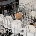 Dishwasher rack with a disinfected sponge, clean dishes, including cups, bowls, and a cutting board.