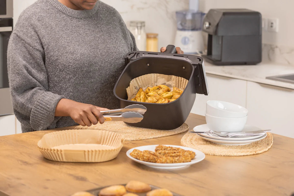 Person using a deep fryer with a disposable liner in a kitchen setting with food and kitchenware.
