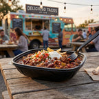 Bowl of chili with a fork on a wooden table in front of a food truck.