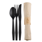 Compostable black spoon, fork, and knife set with a beige paper napkin on a white background