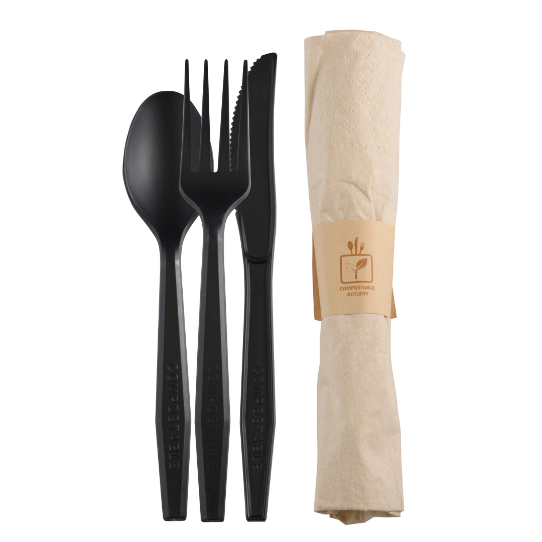 Compostable black spoon, fork, and knife set with a beige paper napkin on a white background