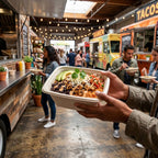 Person holding a take-out bowl of food in a bustling food truck area.