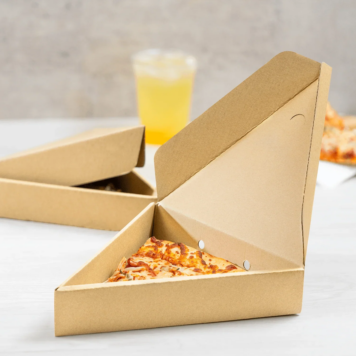 Multiple disposable single-slice pizza boxes on a surface.