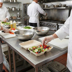 Chefs preparing food in a professional kitchen with salad containers.