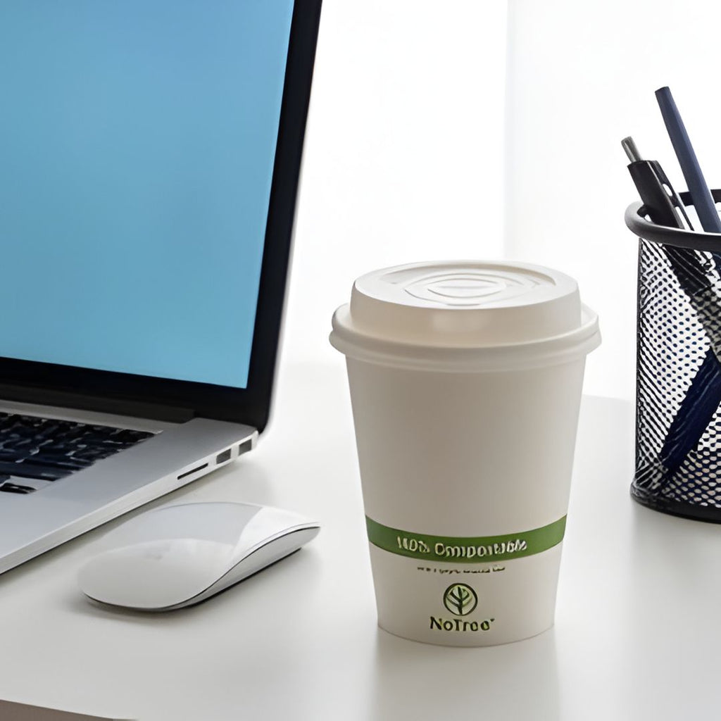 Compostable coffee cup with a lid on a desk with a laptop and mouse