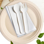White paper cutlery set on a beige plate with green leaves in the background