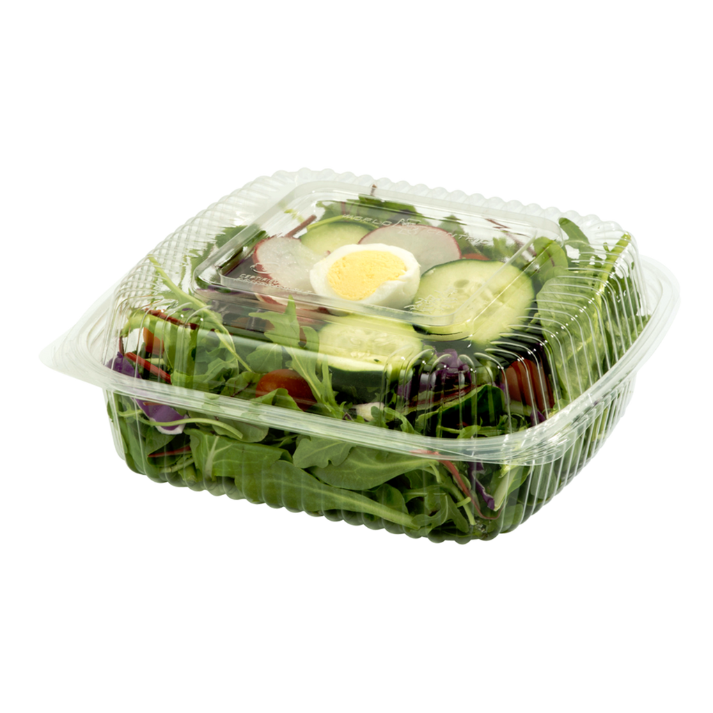 Salad in a clear plastic container with a lid on a white background