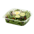 Salad in a clear plastic container with a lid on a white background