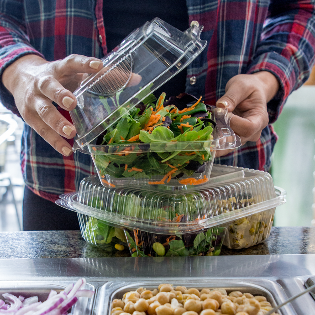 Large clear clamshell and small clear clamshell stacked on top, filed with food at the salad bar.