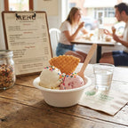 Ice cream bowl with a waffle cone on a wooden table with a menu in the background.