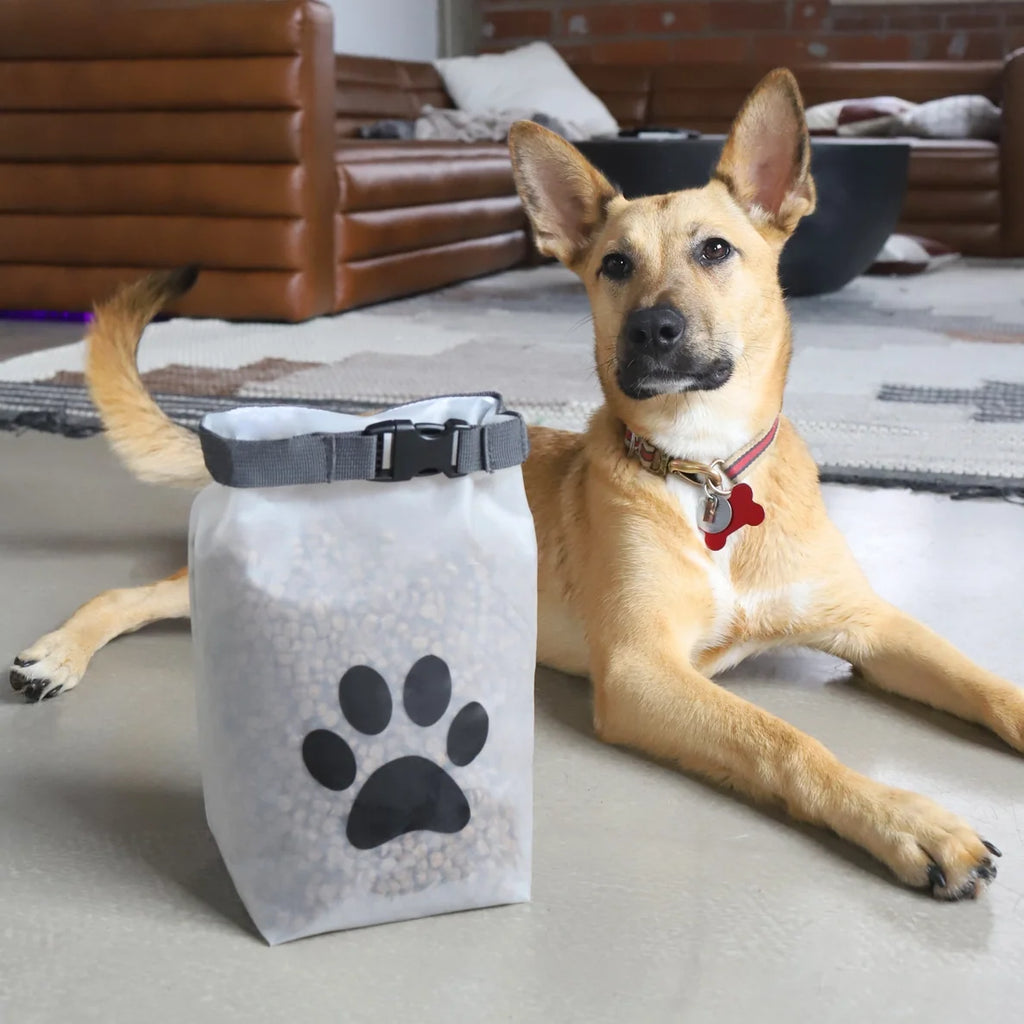 White pet food storage bag with black paw print next to a dog laying down in the living room.