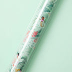 Close up view of mermaid themed wrapping paper on a light green background.